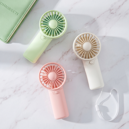 Three Retailark creative handheld fans in pink, green, and white laid out on a marble surface